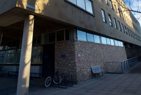 a building entrance with a ramp. There is also a bike and a bench