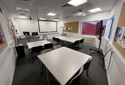 Dalhousie 2S11 - three sets of square tables with chairs, a mobile flat screen tv on the floor and a white screen on the far wall