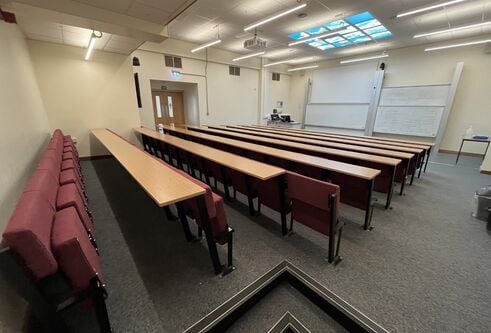 Fulton room J20 with cushioned seats attached to rows and two large white boards at the front of the room