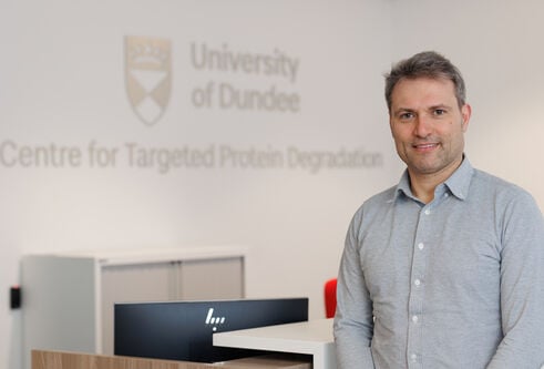 Professor Alessio Ciulli in from of a University of Dundee crest