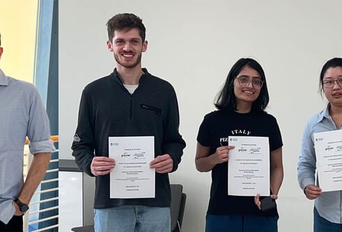 Four people stood smiling. Three holding certificates.