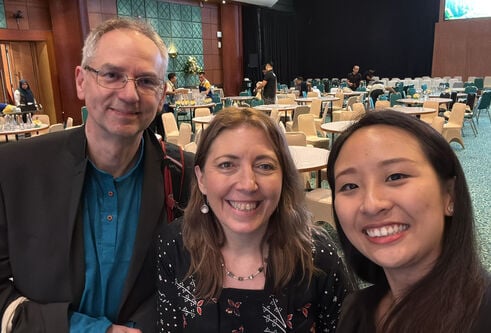 close up shot of three people in front of conference tables and chairs