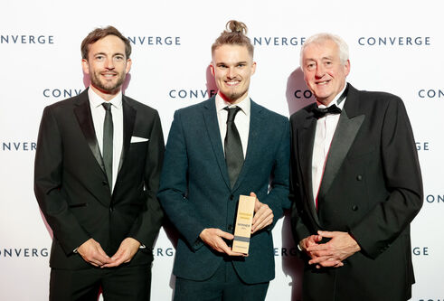 Nathan Dudley, Create Change Challenge winner, with David McBeth and Brian McNichol of the University, with award standing infront of a branded backdrop
