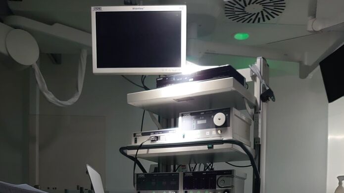 Interior of a hospital room showcasing a wall-mounted screen and a laparoscopy computer setup on a desk