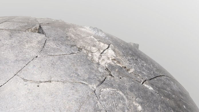 A section of a grey concrete looking sphere, against a pale grey background.
