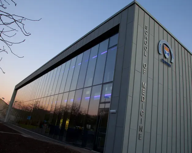 The exterior of the School of Medicine library, with an orange sunset behind it