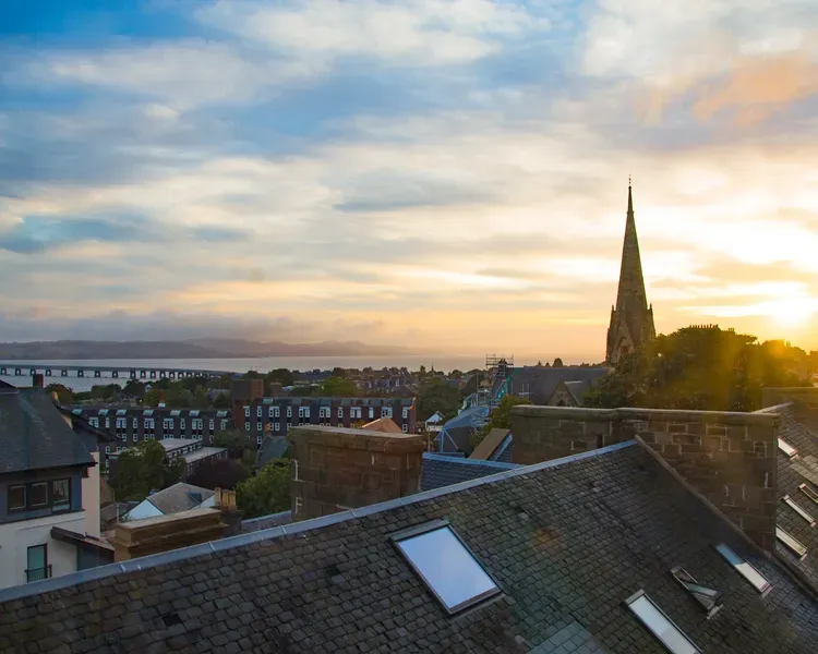 A sunset view over Dundee rooftops toward the Tay Bridge