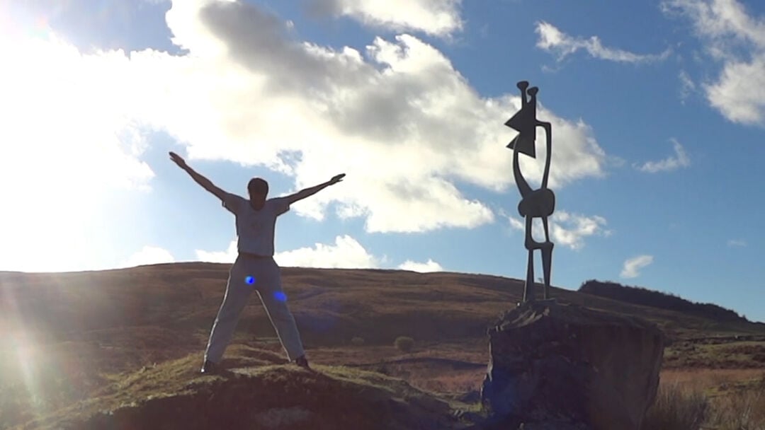 man with outstretched arms on hill