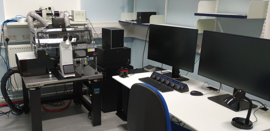 large microscope next to two computer screens