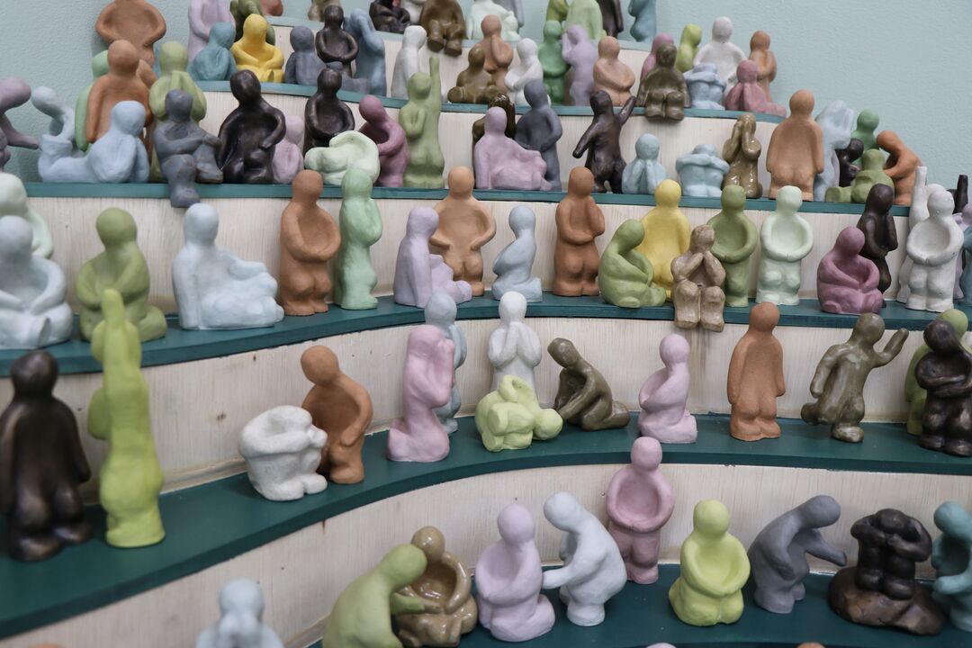 group of small, faceless ceramic figures on small shelves, all gathered together