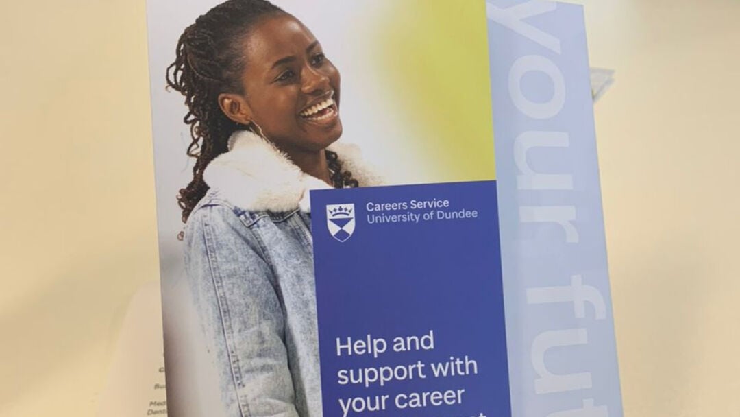 Student holding a brochure in her hand with an image of herself and with text that reads, Help and Support your career.