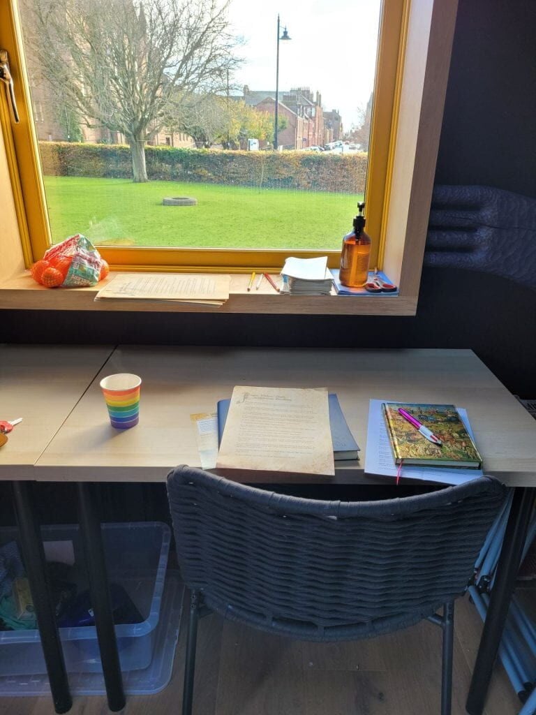 A desk set below a window with papers on top